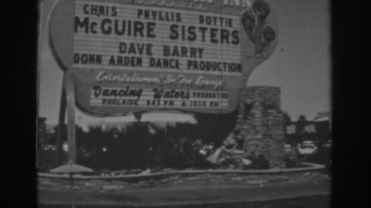 1962 Las Vegas home-movie frame showing a resort marquee for the McGuire Sisters, Dave Barry, and poolside entertainment near palms and stonework.
