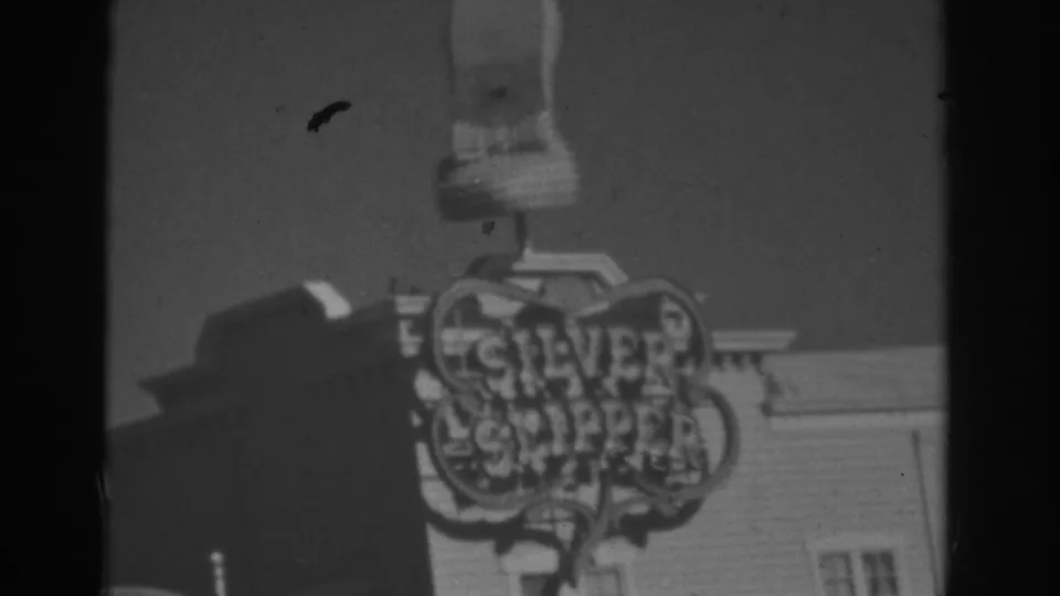 Low-angle 1962 Las Vegas frame of the shoe-shaped sign over Silver Slipper lettering and a building corner.