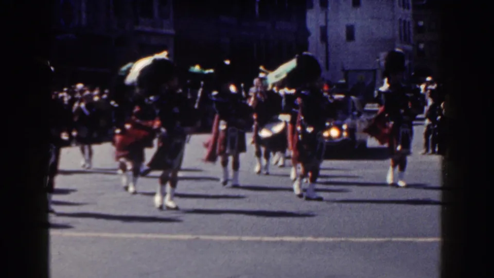 Kilted musicians march in formation on a New York City street during the 1962 Irish parade footage.