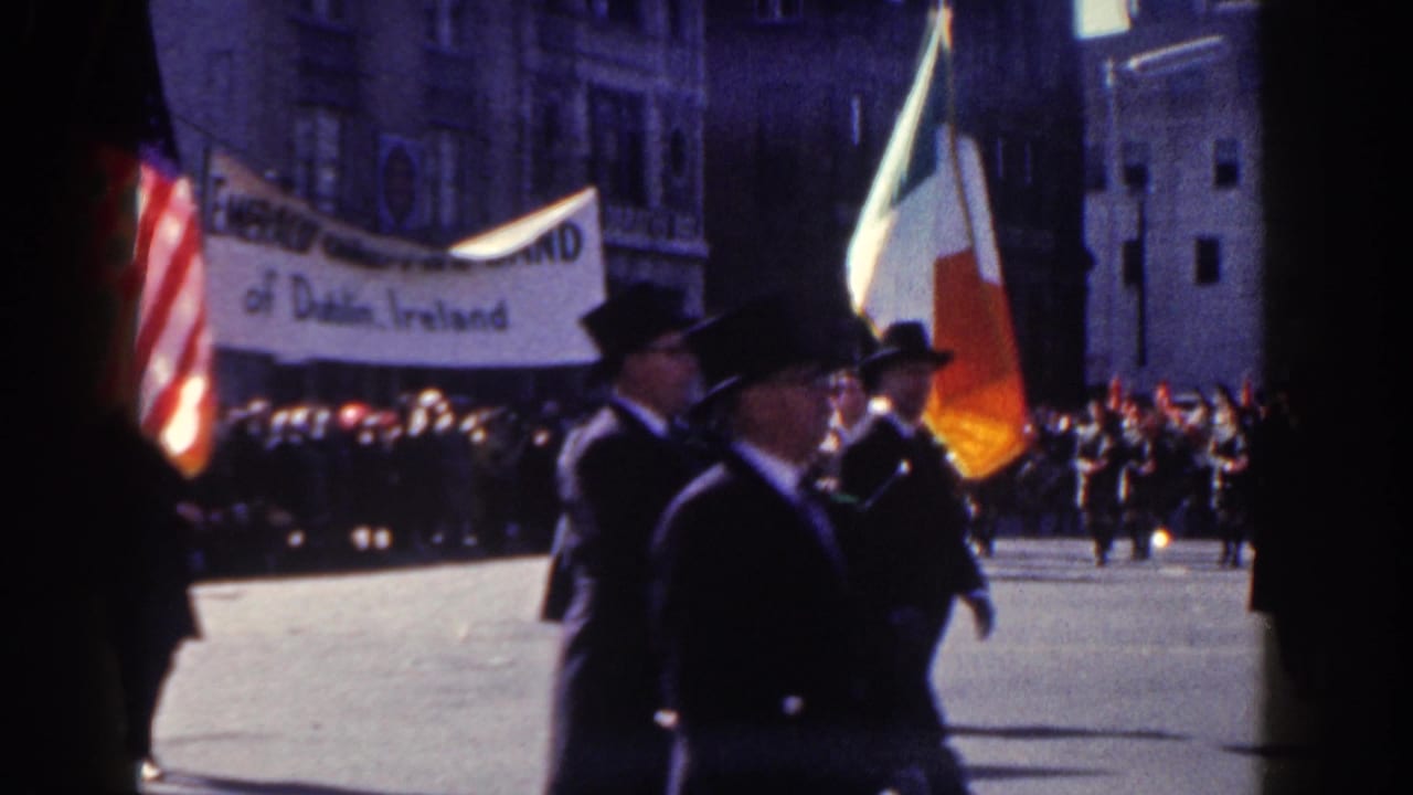 Parade marchers carry American and Irish flags beside a banner for the Emerald Girls Pipe Band.