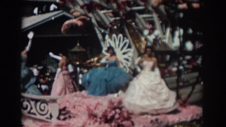 Near the end of the clip, the 1962 Pasadena float shows riders in blue, pink, and white dresses beside a white fan-like ornament and floral trim.