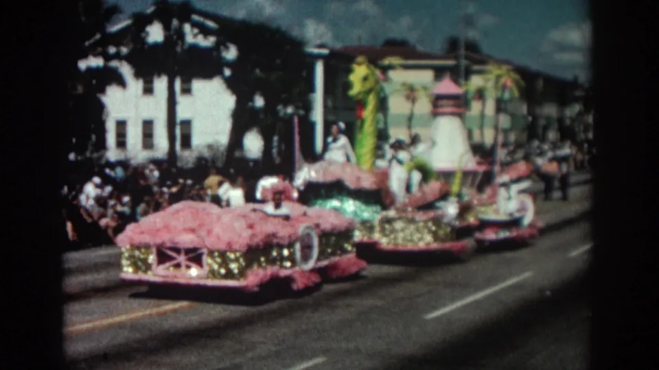 1962 Pasadena parade footage showing a pink and gold float with a green sea monster element moving past sidewalk spectators.