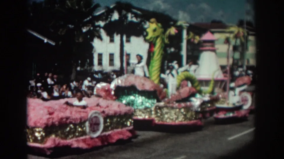 Close curbside view of the 1962 Pasadena parade float, with pink fabric surfaces, gold sequins, and a tall green sea monster form.