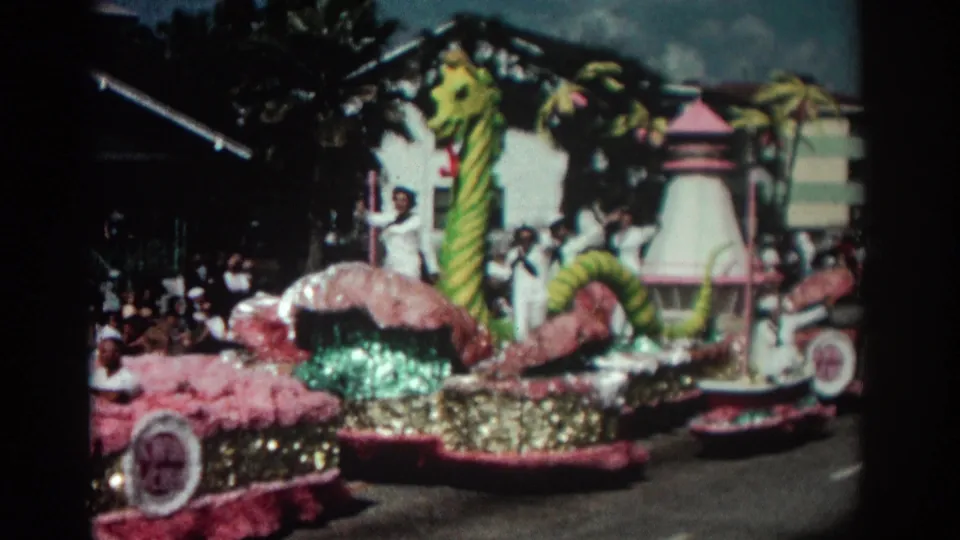 A white-uniformed rider waves beside the green sea monster form as the pink and gold float continues down the Pasadena parade route.