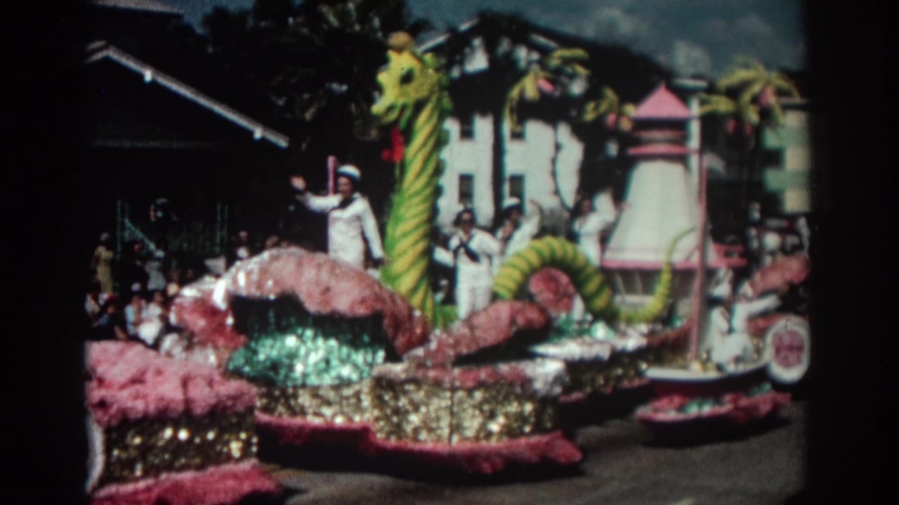 Parade float with a striped sea serpent and sailors in white uniforms waving to spectators.