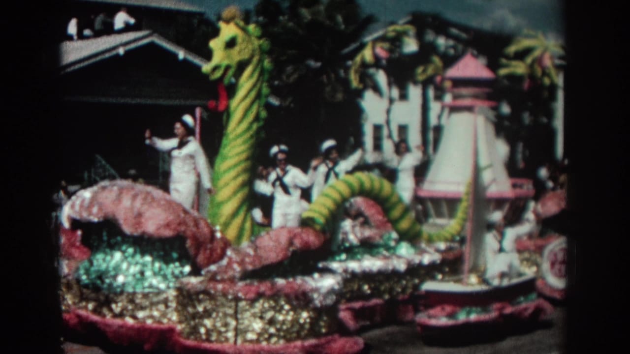 Sea serpent parade float with sailors, a small sailboat, and spectators along the street.