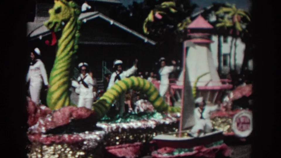 1962 Pasadena parade view centered on the striped sea serpent body, sailors in white uniforms, and pink decorative float pieces.