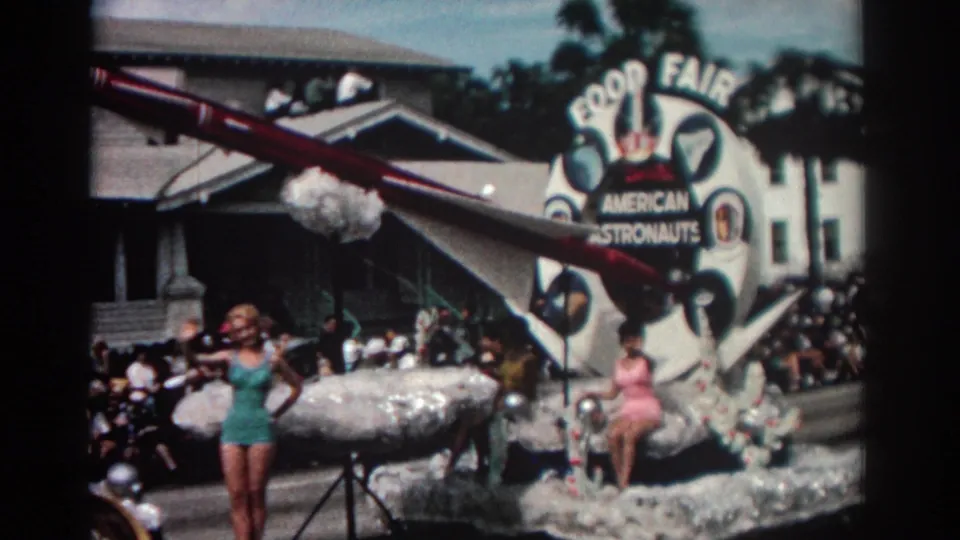 1962 Pasadena frame showing a rocket prop over a decorated parade float with women, spectators, and Food Fair lettering.