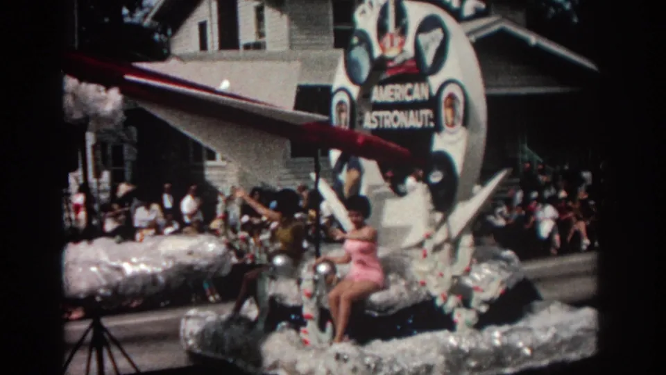 A closer 1962 Pasadena parade view shows the Food Fair astronaut sign, rocket prop, silver float surface, and performers riding through the street.