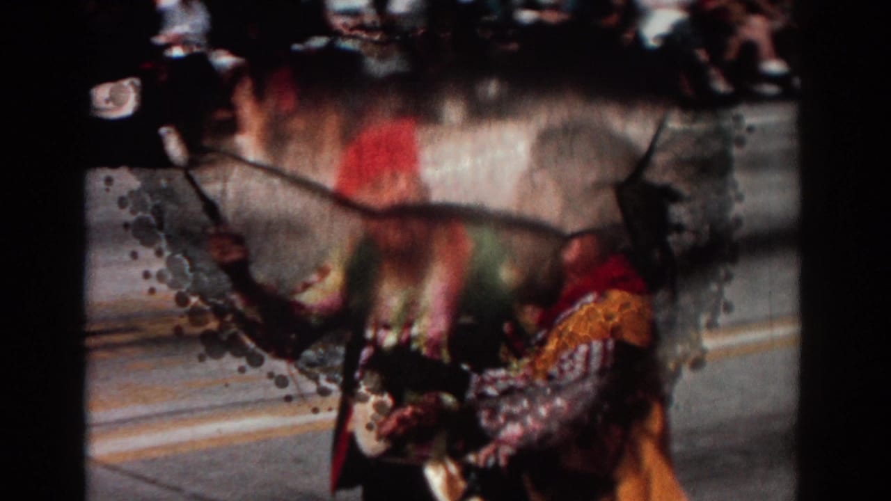 Costumed performer partly obscured by film damage or blur near the parade route.