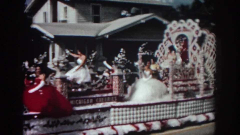 Close view of the 1962 Pasadena parade float shows women in white and red dresses, floral columns, latticework, and partial CHICAGO CHERRIES text.