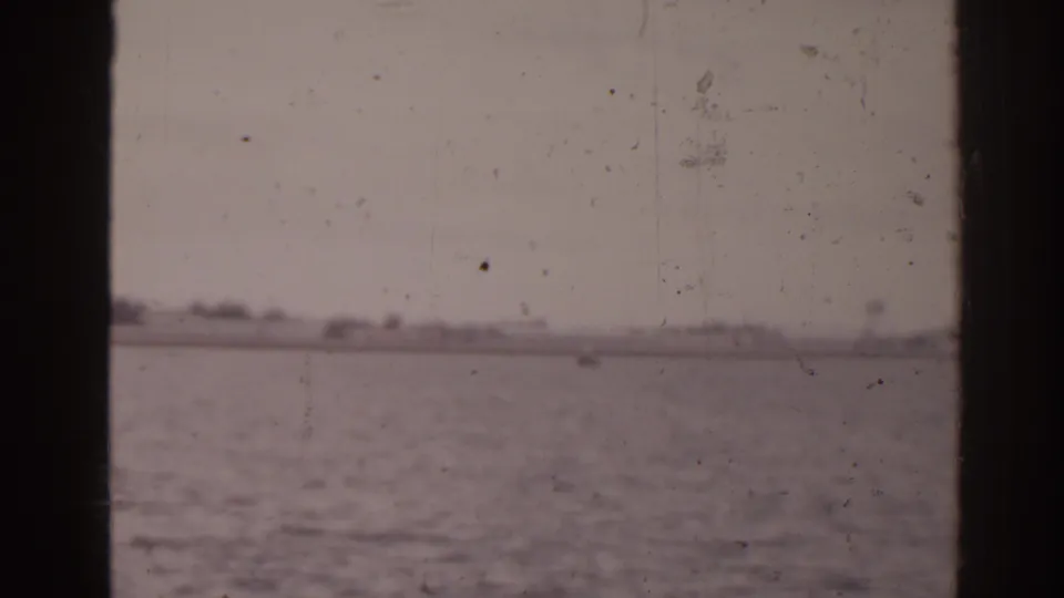 Soft 8mm Florida coastal view showing open water, pale sky, and low distant land from a moving boat.