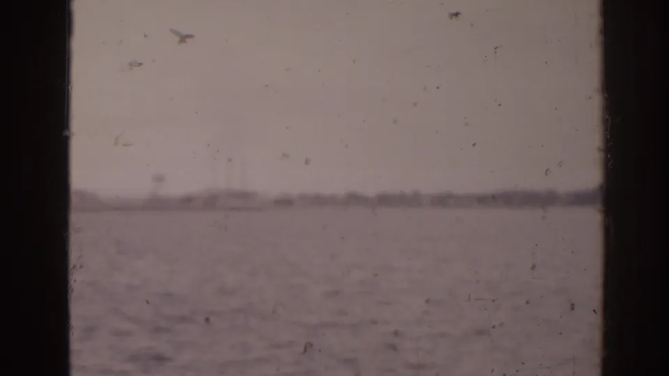 Muted 8mm boat-view frame from Florida in 1963, with calm sea, hazy sky, and distant shoreline.
