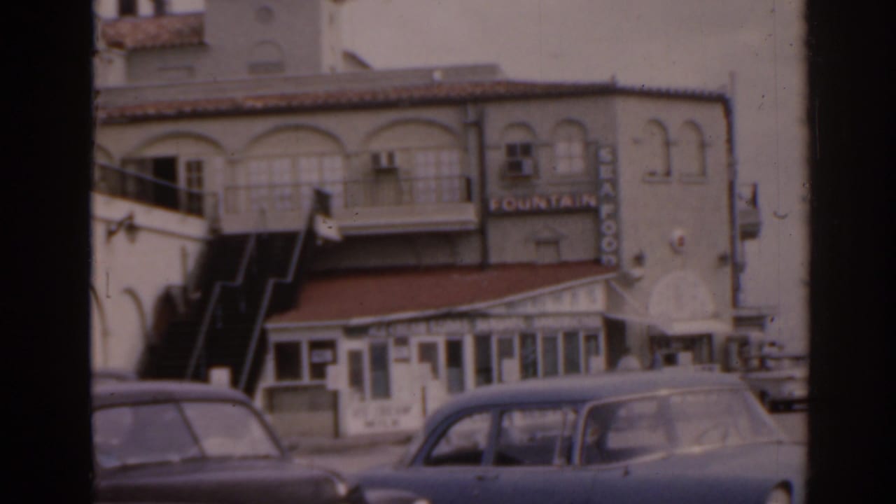 Two-story building with arched windows, storefront, Fountain sign, and parked cars.
