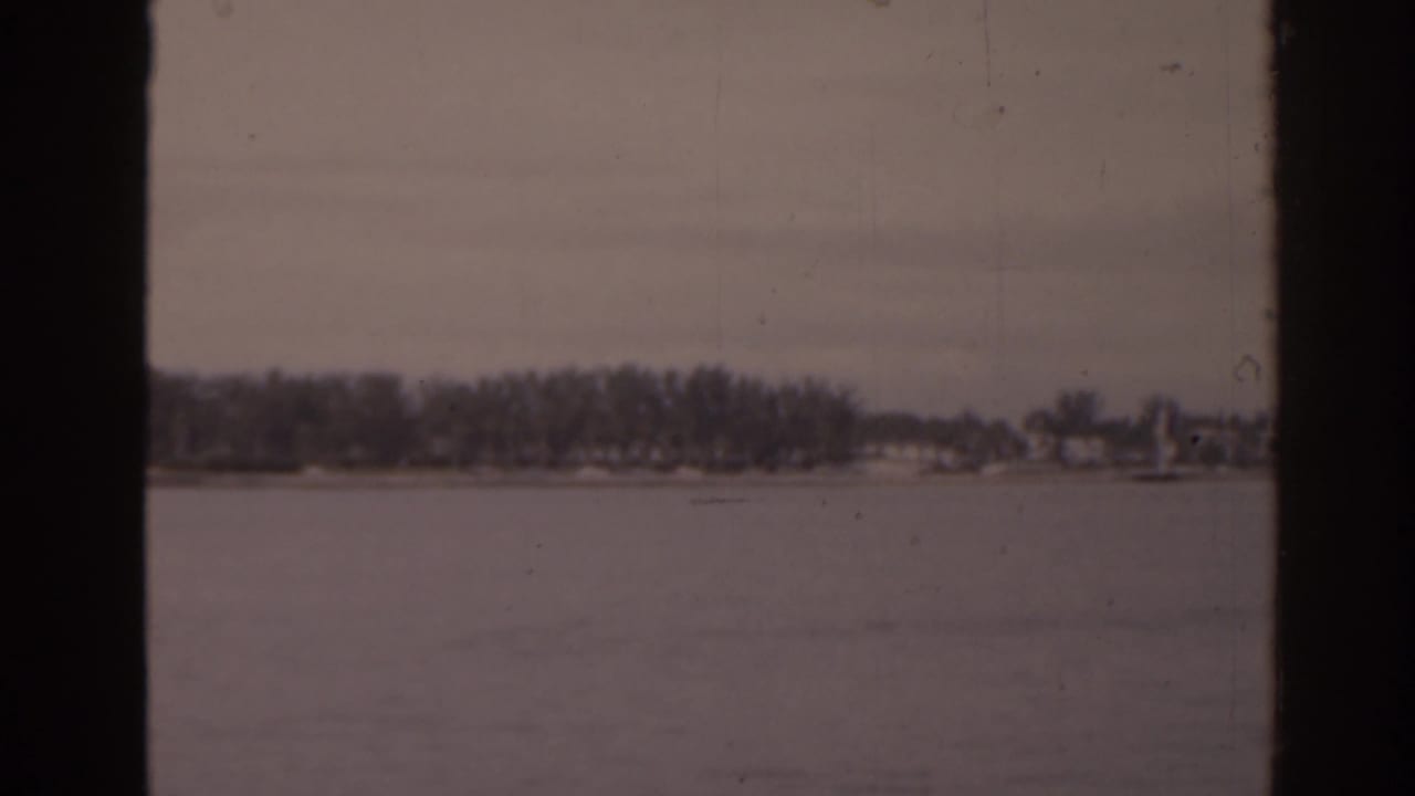 Wide lake surface with a distant wooded shoreline and dark frame edges.