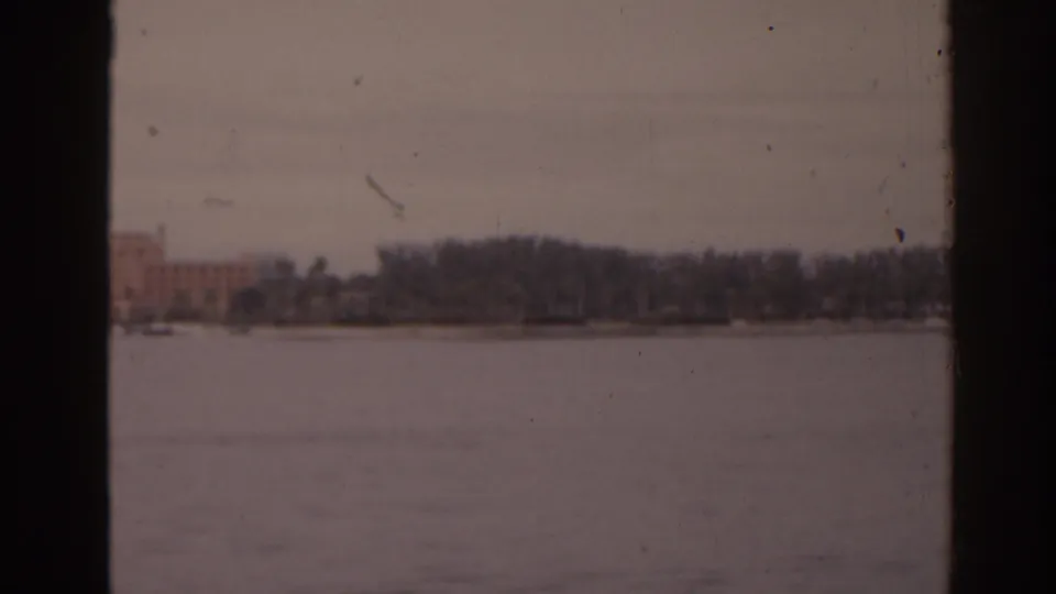 Faded 8mm view across a Florida lake toward trees and a low shoreline building in 1963.