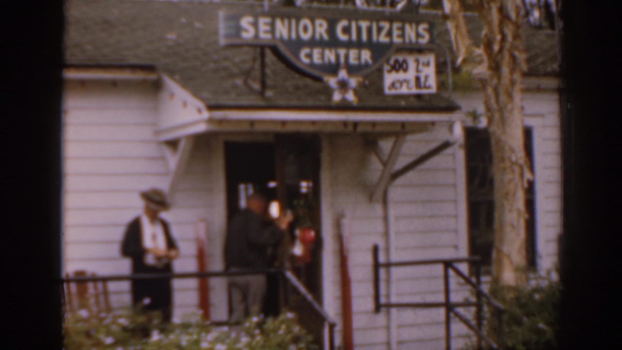 Two adults outside a Senior Citizens Center entrance with signs above the doorway.
