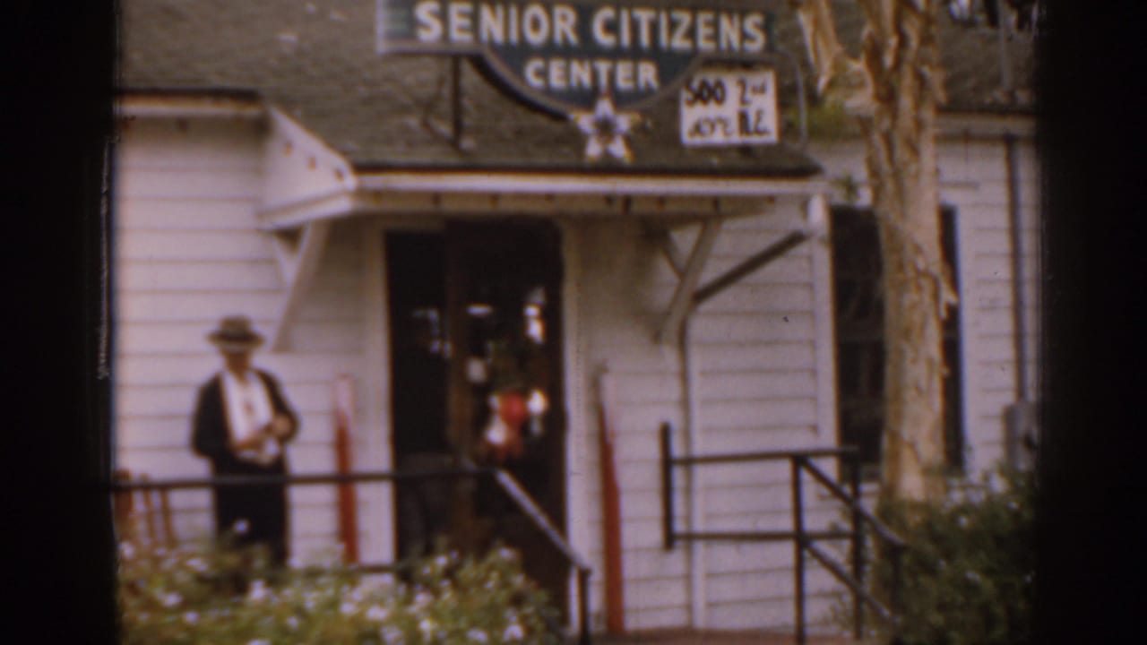 Adult near the doorway of a Senior Citizens Center building with entrance rails visible.