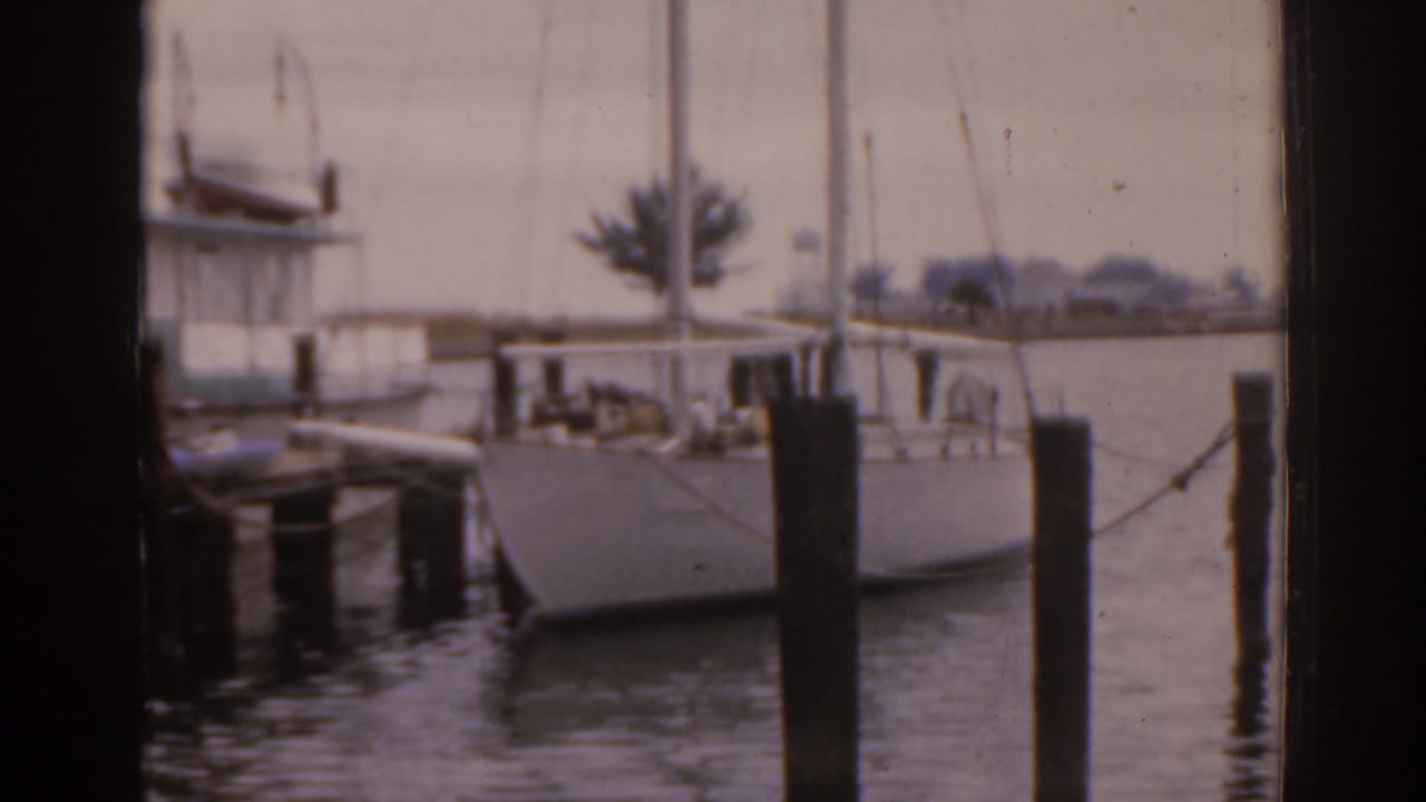 Sailboat at a dock seen through dark vertical frame edges.