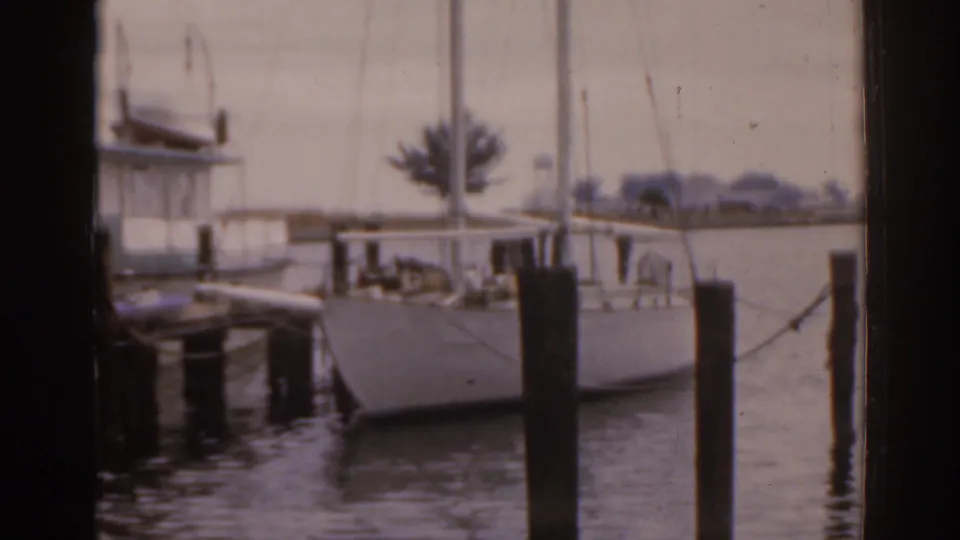 A docked sailboat sits in calm Florida marina water, partially framed by dark vertical edges from the 8mm scan or shooting position.