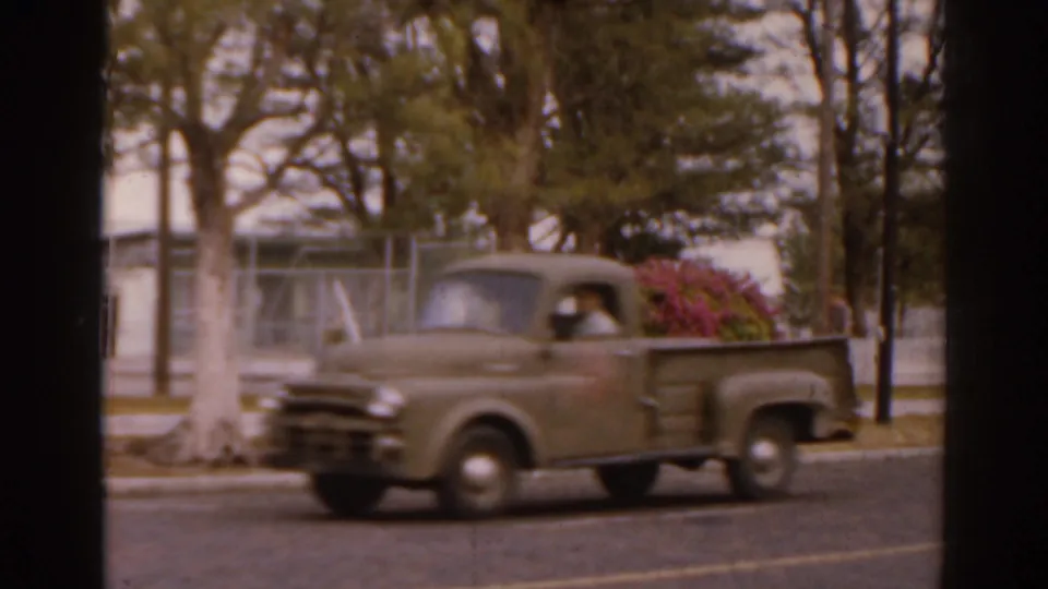 1963 Florida home-movie frame showing a green pickup truck passing trees, with a driver visible through the cab window.