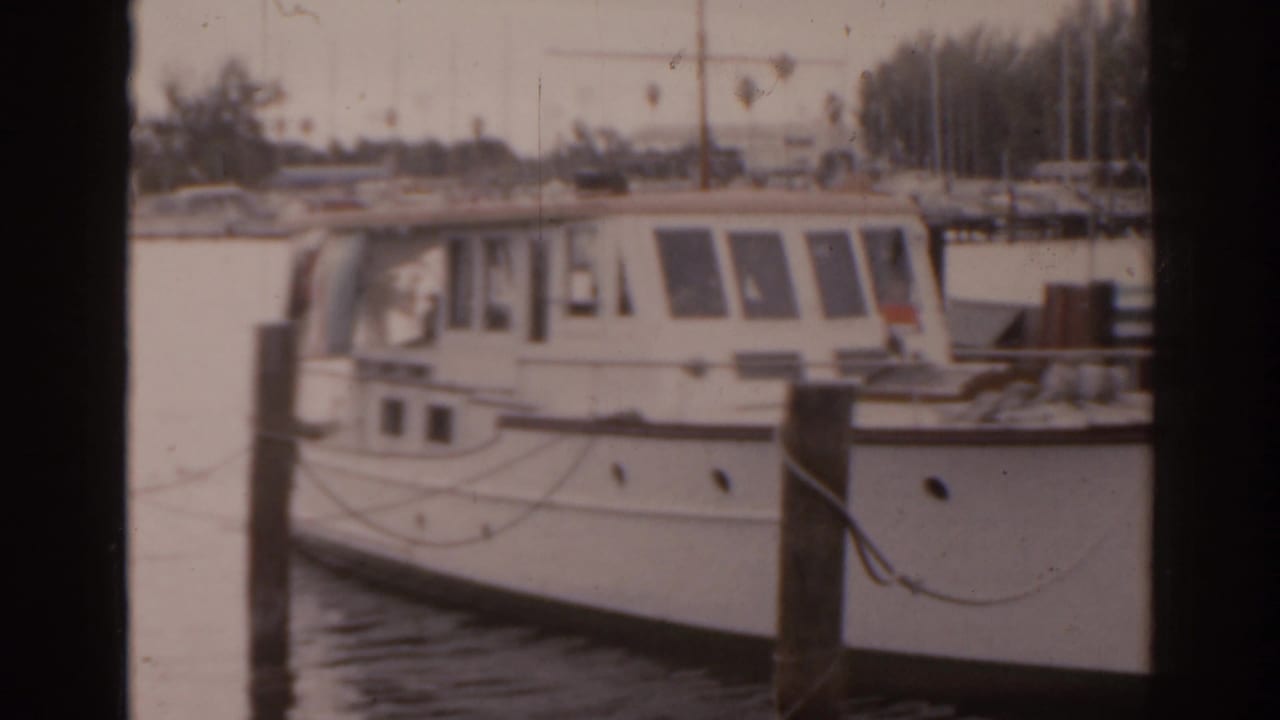 White cabin motorboat docked beside pilings at a marina.