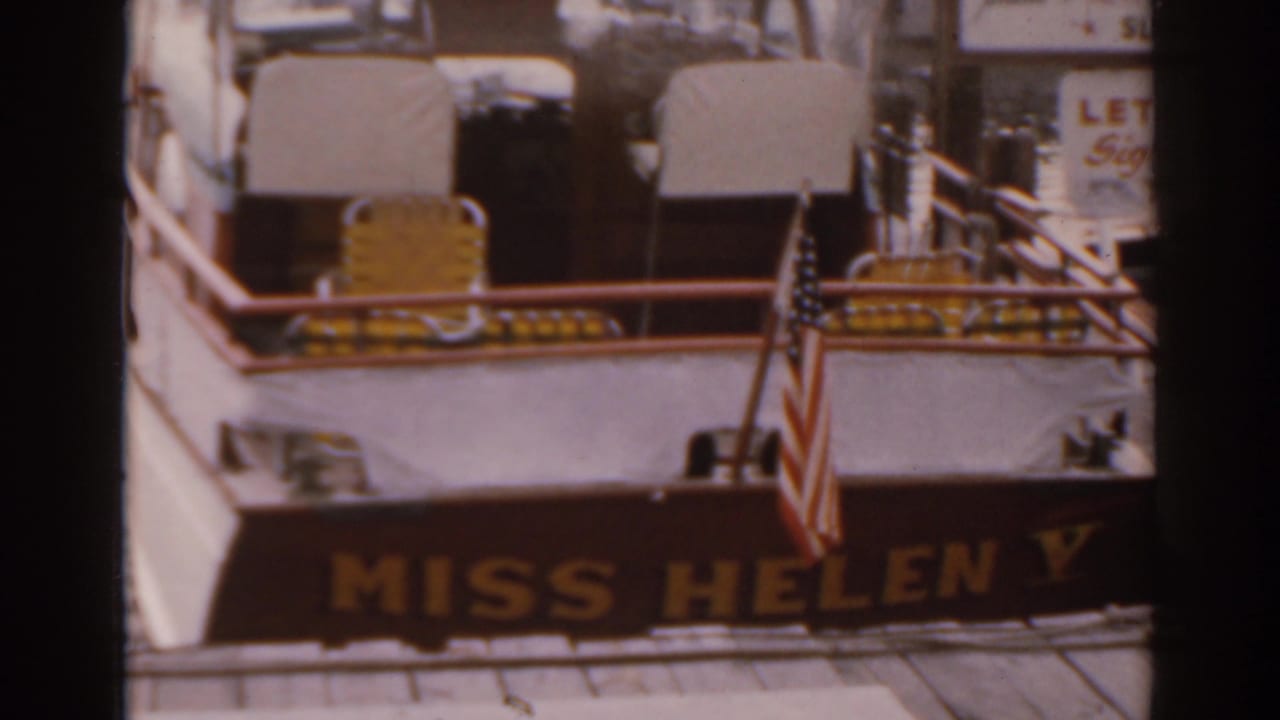 Docked Miss Helen V riverboat stern with flag and deck seating in soft focus.