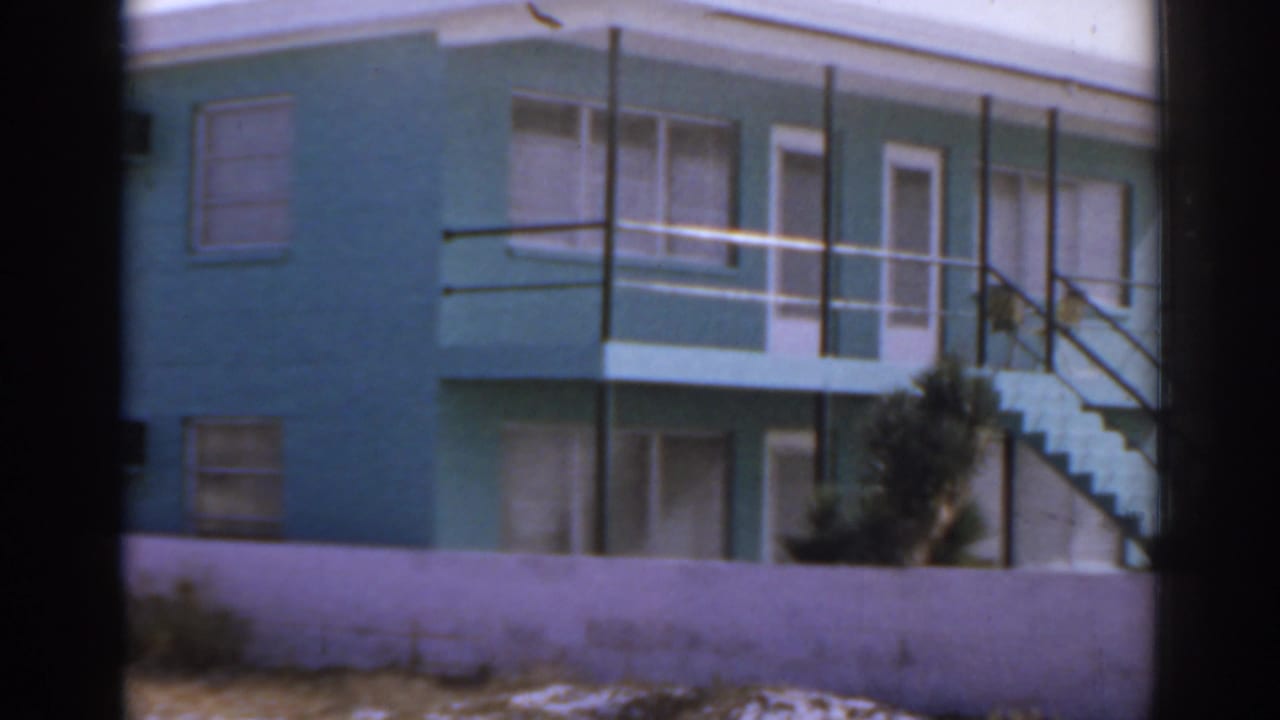 Similar view of the turquoise building with balcony, stairs, and low wall.