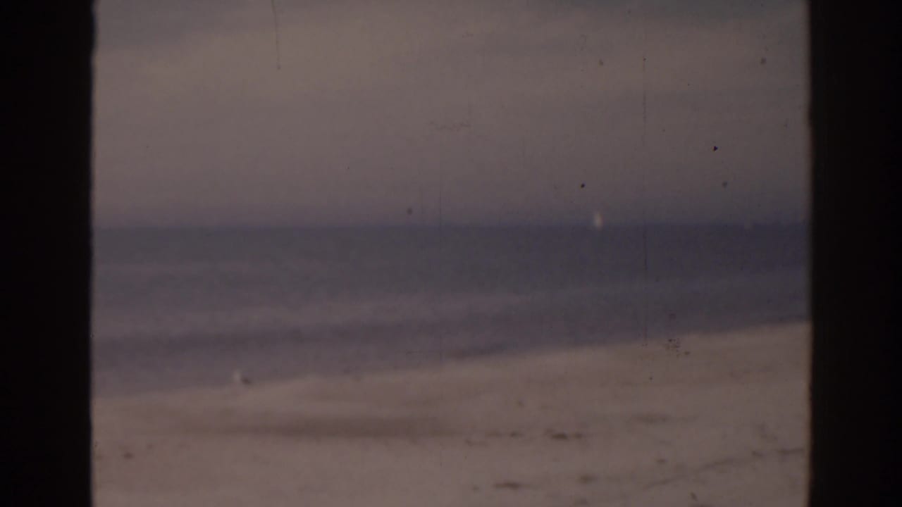 Quiet sandy beach with ocean waves under an overcast sky.
