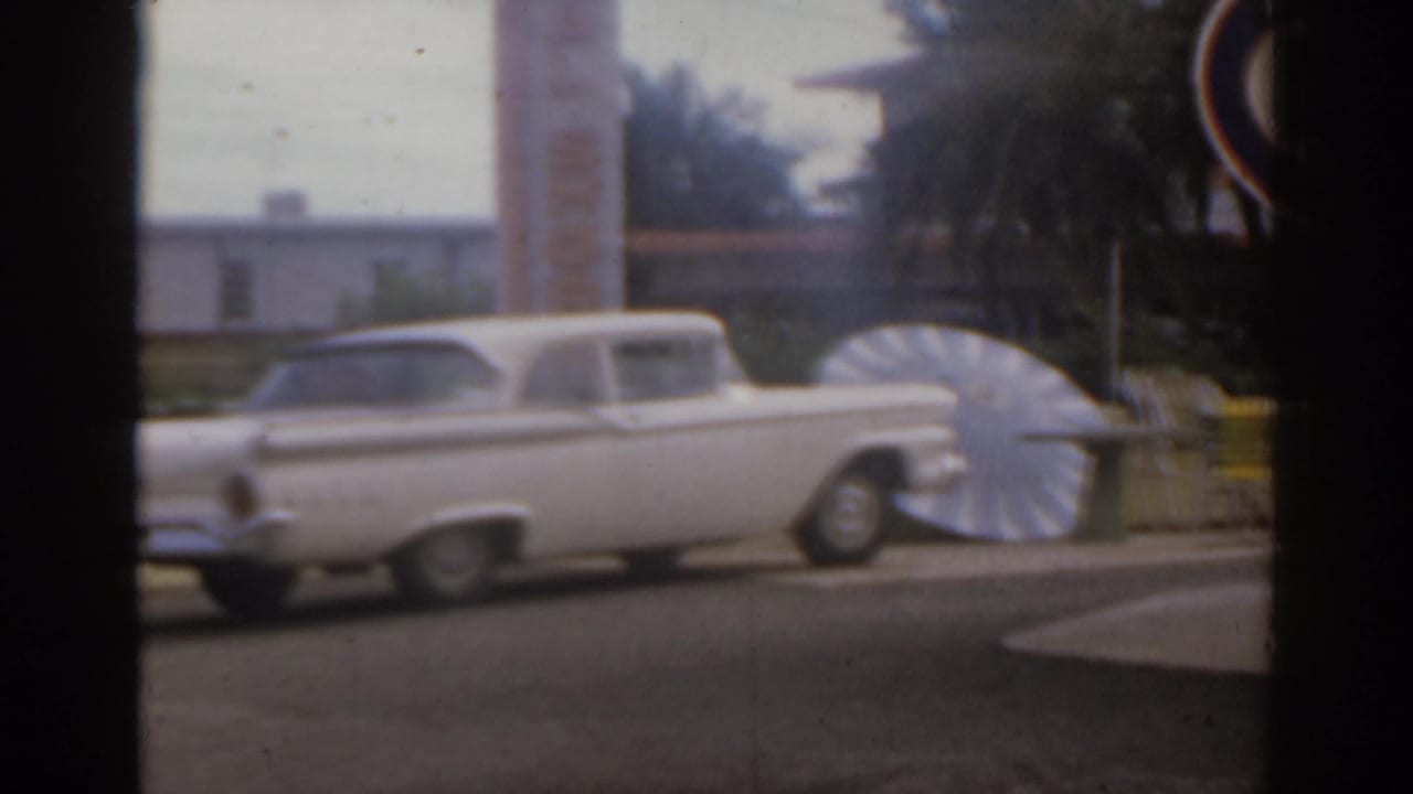 White parked car beside a large fan-shaped roadside display.