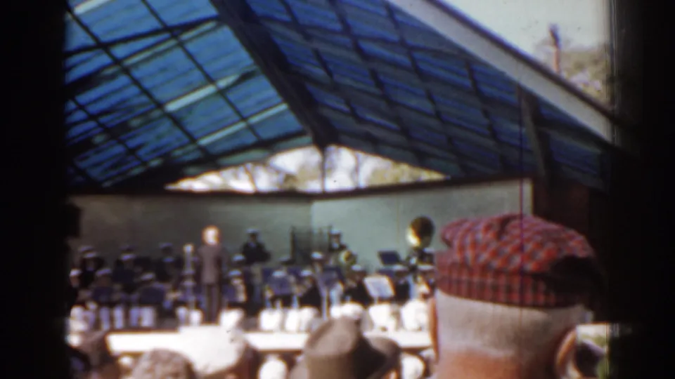 1963 Florida 8mm frame showing a visitor's obstructed audience view of musicians performing under a blue glass roof.