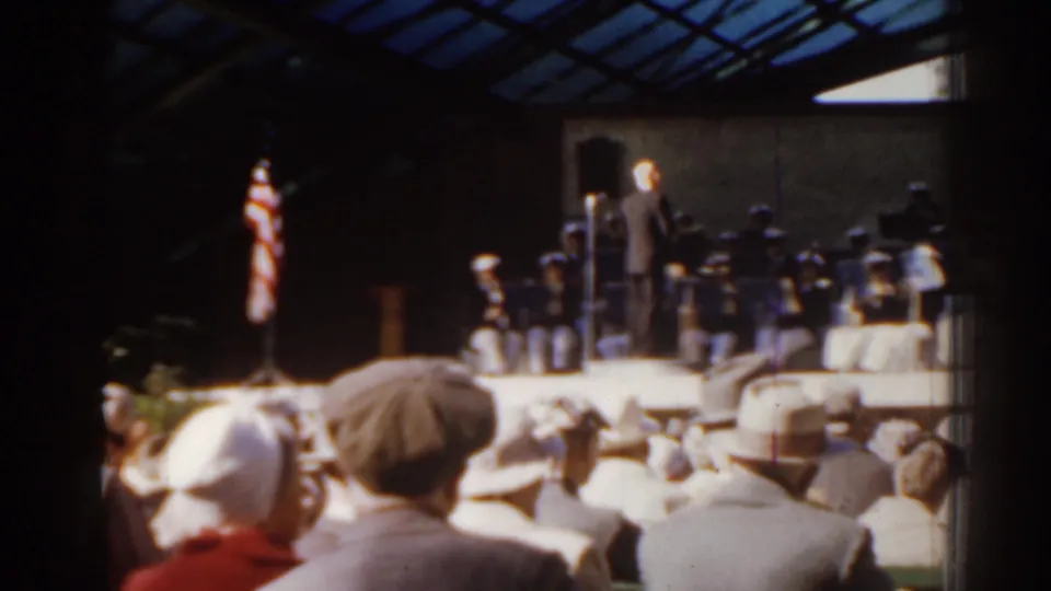 1963 Florida home-movie view of a conductor and band performing under a pavilion with spectators seated in front.
