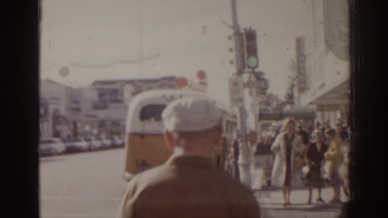 Pedestrians and a yellow-and-white bus on a bright city street.