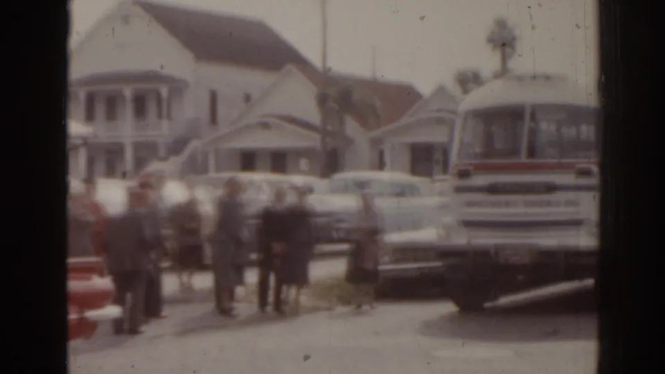 1963 Florida street gathering with uniformed adults, a red HAV-A-TAMPA car, white bus, and parked period cars.