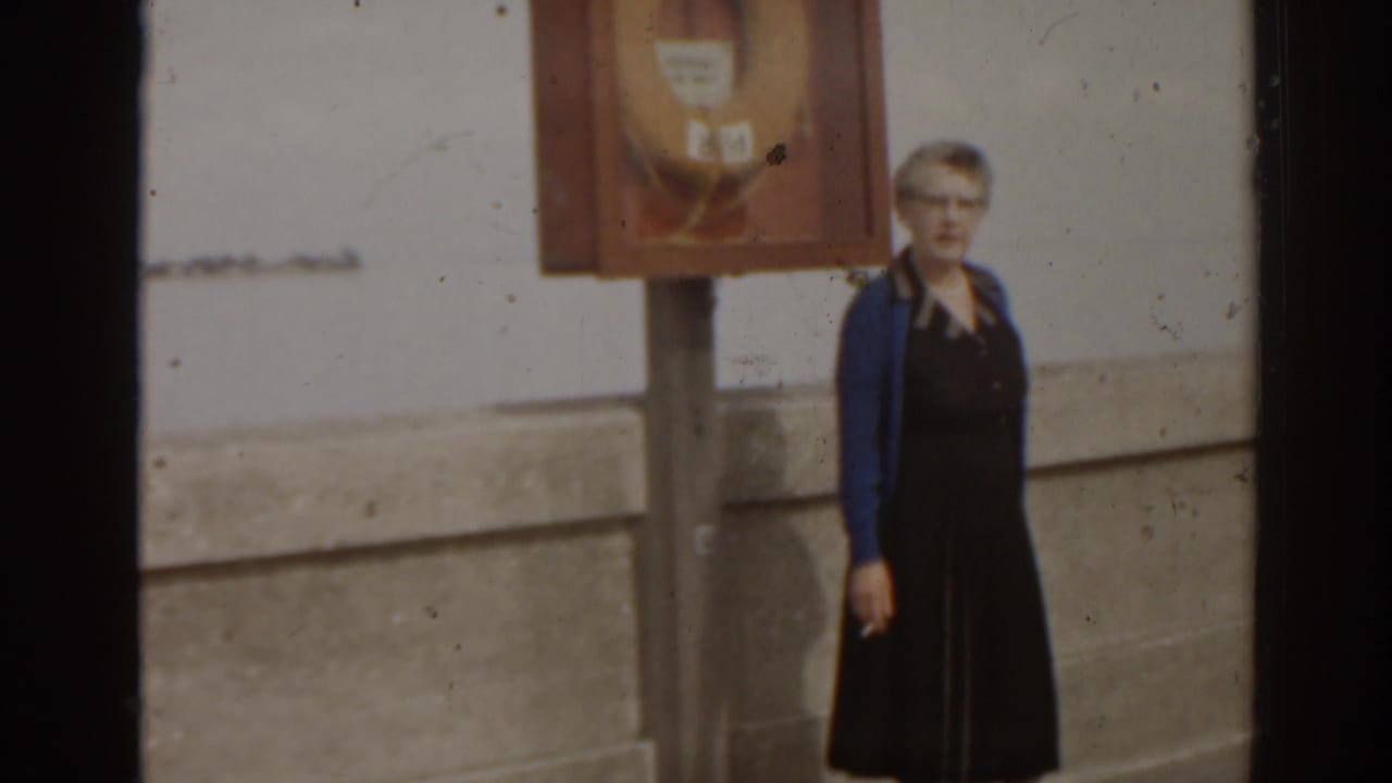 Woman standing on a concrete pier beside a life preserver cabinet.