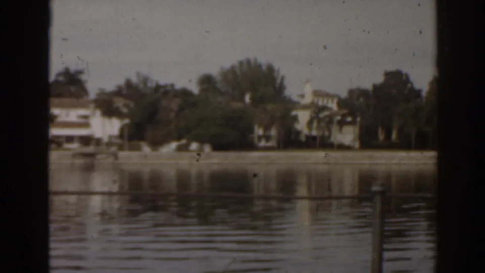 1963 Florida lake shoreline with waterfront houses, palm trees, and reflections on rippled water.