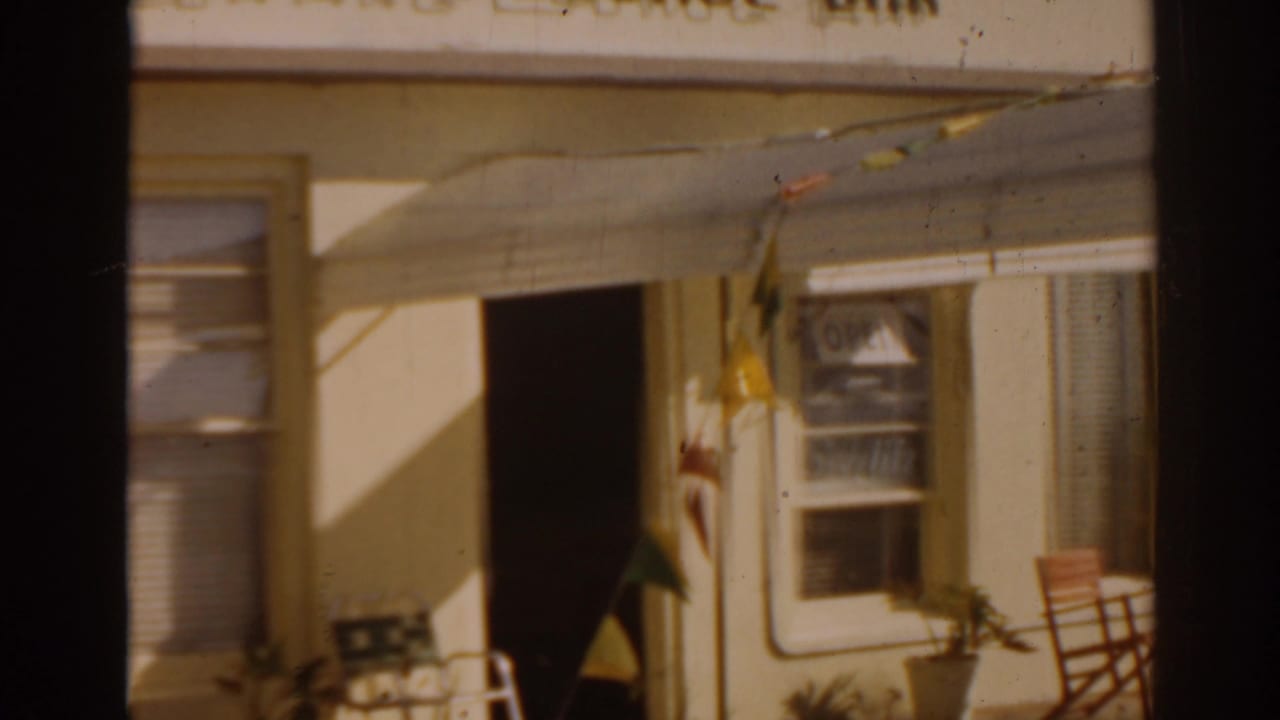 Cocktail lounge entrance with awning, window, bunting, doorway, and patio items near the wall.