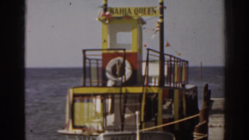 A close 1963 Florida view of the Bahia Queen ferry cabin, showing the vessel name, railings, life ring, dock rope, and sea horizon.