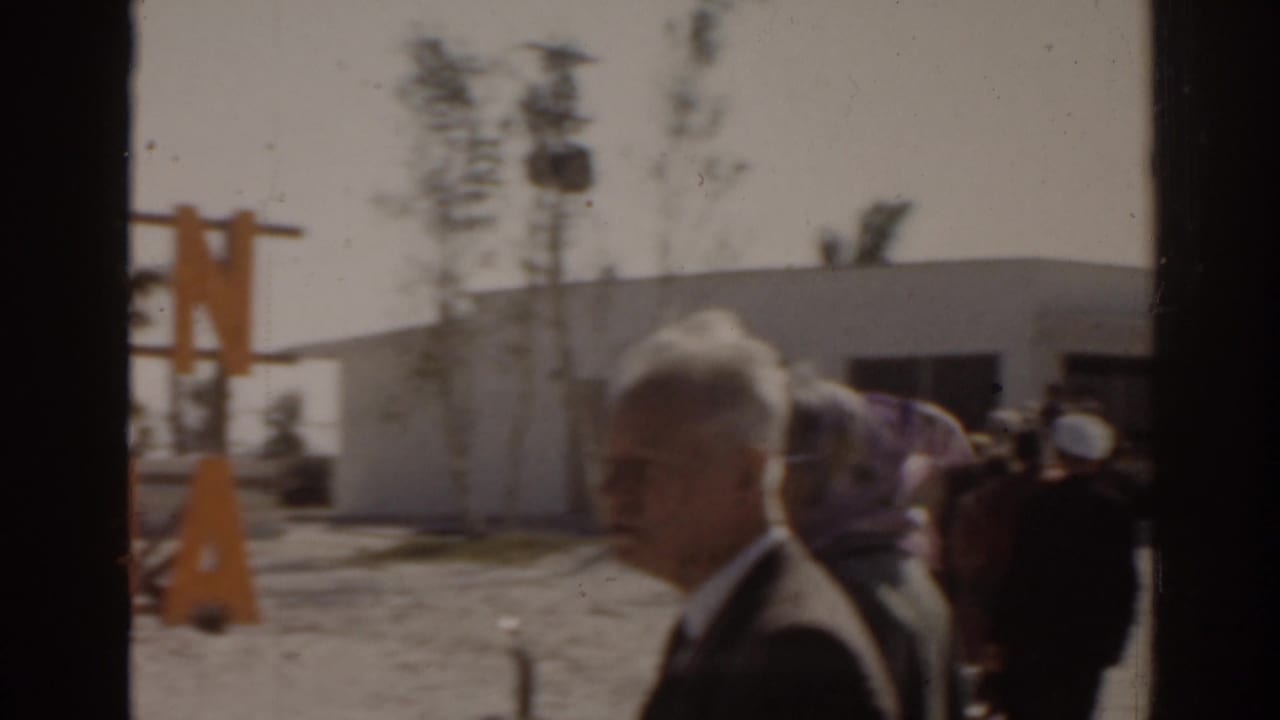 1963 Florida frame with adults gathered outside a low white building near the Ruskin Marina area.