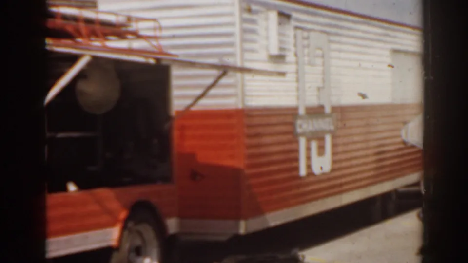 1963 Florida 8mm frame showing the rear side of a red and white food truck, including corrugated panels, a circular vent, and a small side fixture.