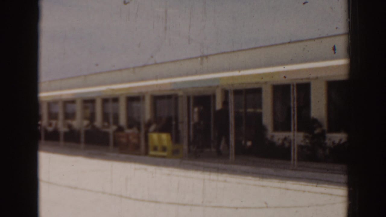 Building exterior with a shaded walkway and small objects near the entrance.