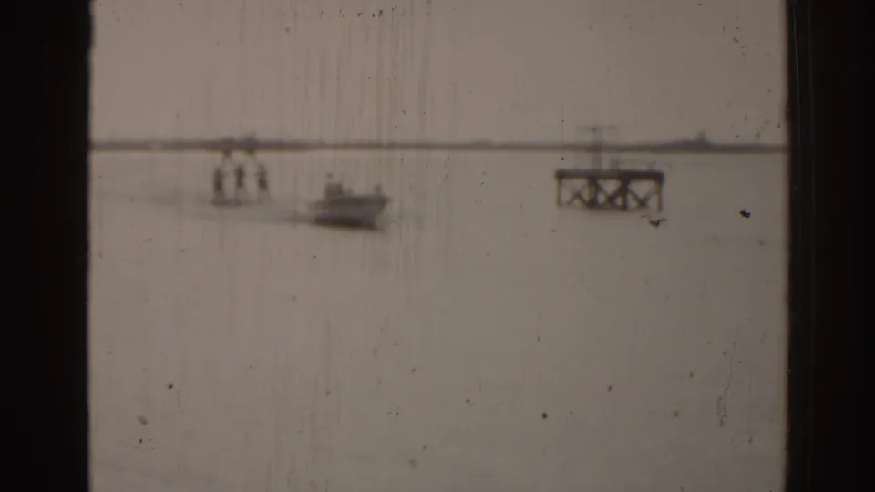 Soft 8mm view of open Florida water with a distant boat, shoreline, and a small dock or platform structure.