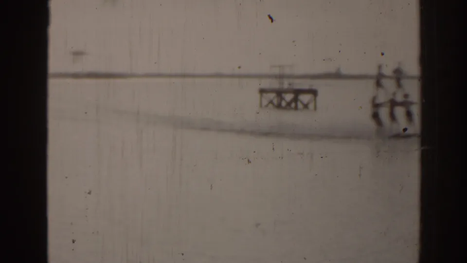 1963 Florida 8mm frame showing distant figures on a pier or bridge structure across calm water.