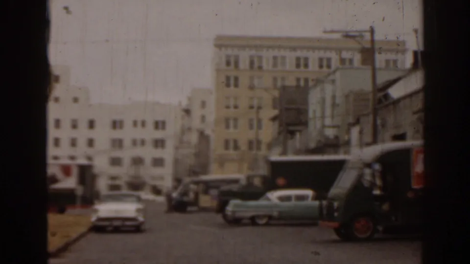 1963 Florida 8mm street view with mid-century cars, utility poles, older buildings, and a branded delivery truck partly visible.