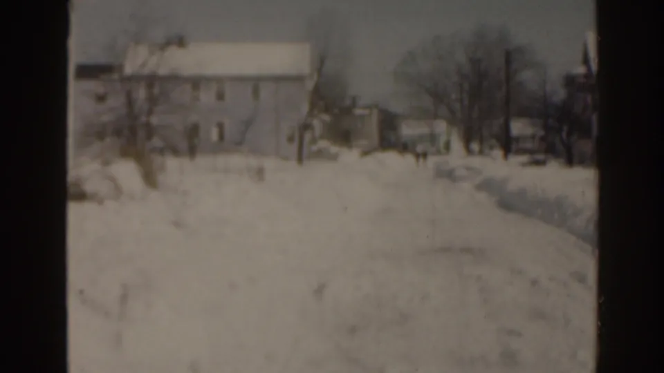 1963 Florida home-movie frame of a snow-blanketed residential yard, with a house, bare trees, fence line, and deep snow in view.