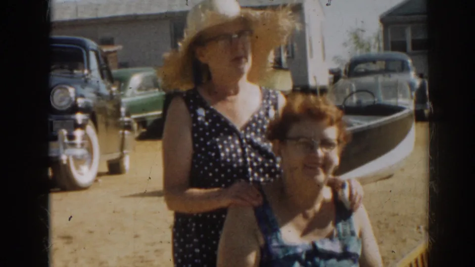 A second woman in a wide straw hat and polka-dot dress joins the seated woman for a posed 1963 New Jersey shore moment.