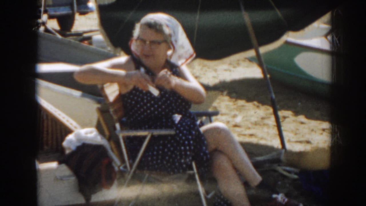 Seated woman adjusts her clothing while sitting in a beach chair.