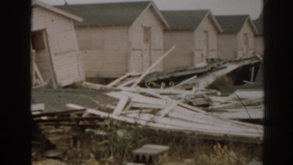 1963 New Jersey home-movie view of tan shacks, collapsed lumber, and torn building material after apparent storm damage.