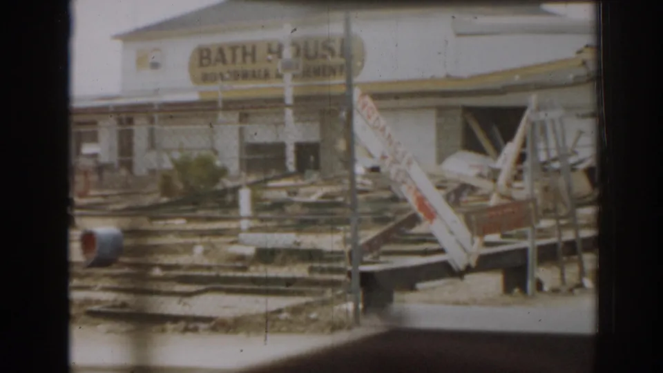 1963 New Jersey 8mm frame showing a bath house sign above scattered debris and collapsed-looking structures.