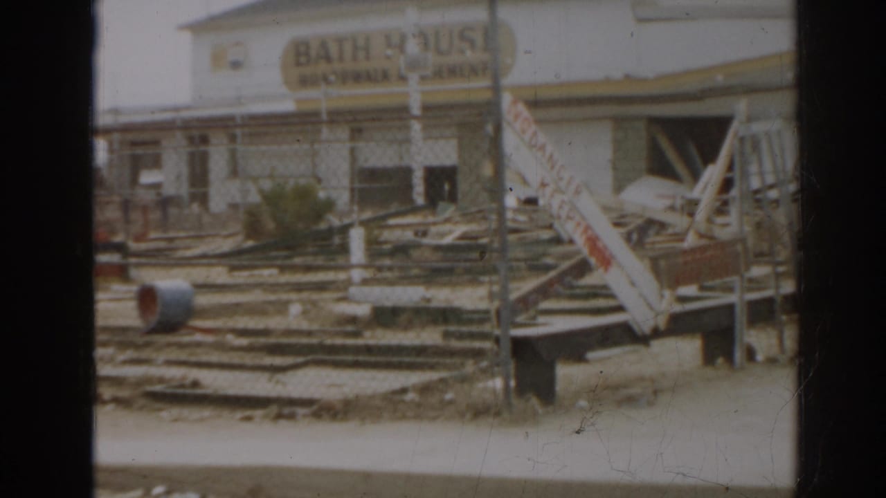 Bath house sign above debris and slanted damaged structures.